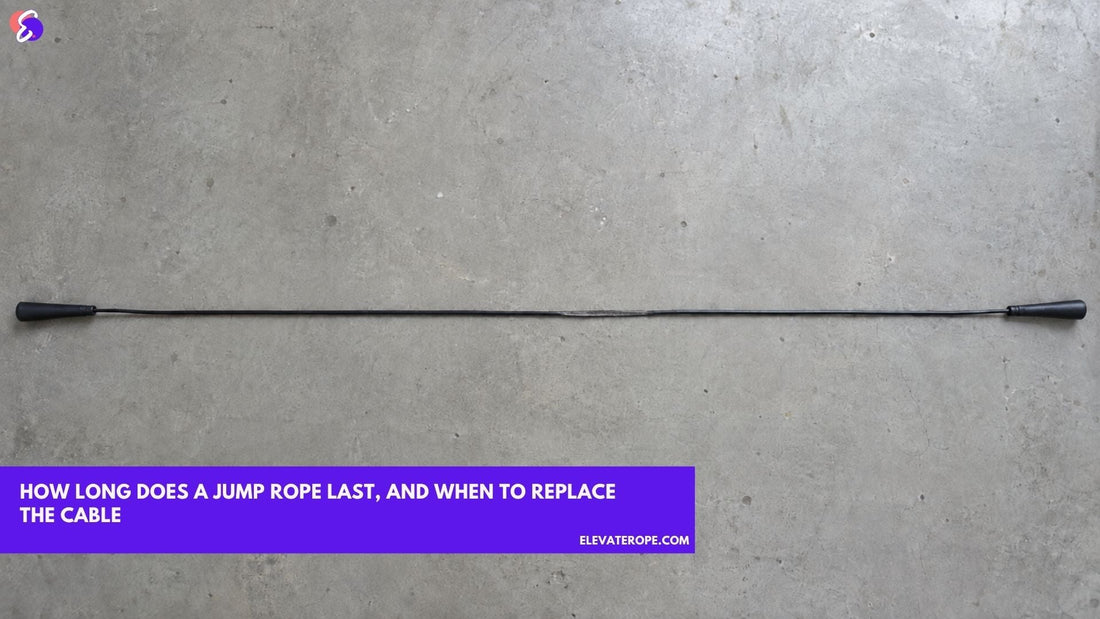 Overhead view of a black PVC jump rope laid out straight on a concrete floor, with one section visibly flattened and dulled where it meets the ground each turn.